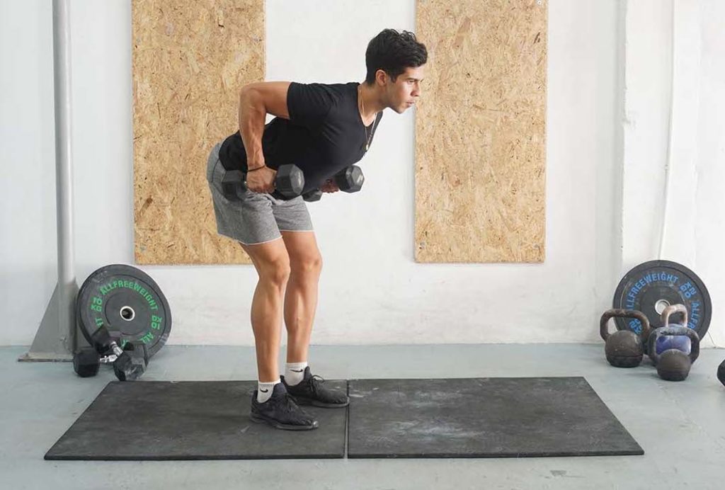 A man performing a bent over row using a single dumbbell in a gym setting.