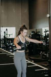 A person performing a lateral raise to illustrate movement occurring in the frontal plane.