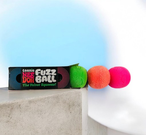 Three small, colorful fuzzy stress balls in pink, blue, and purple.