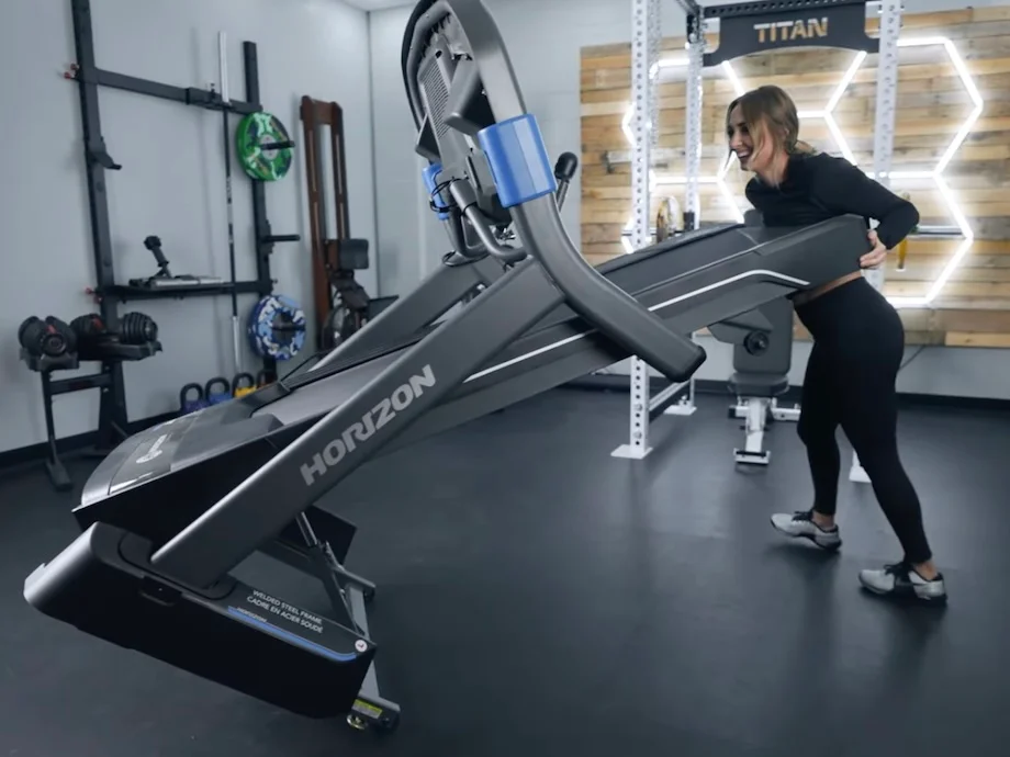 A fitness expert moving a Horizon treadmill to test its portability and storage features.