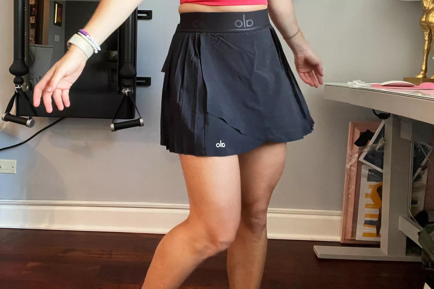 A woman performing a dynamic workout movement in a black Alo Yoga skirt.