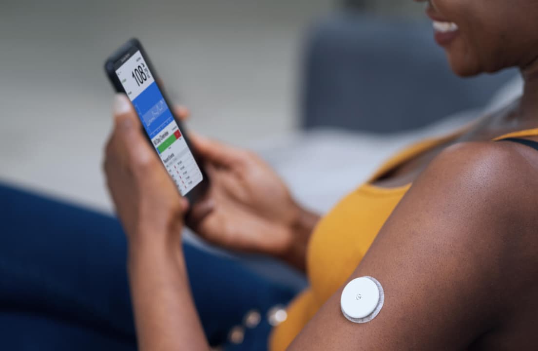 A person reviewing their glucose levels on a smartphone to understand metabolic trends and Time in Range.