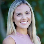 A smiling woman in an outdoor setting representing wellness and fitness.