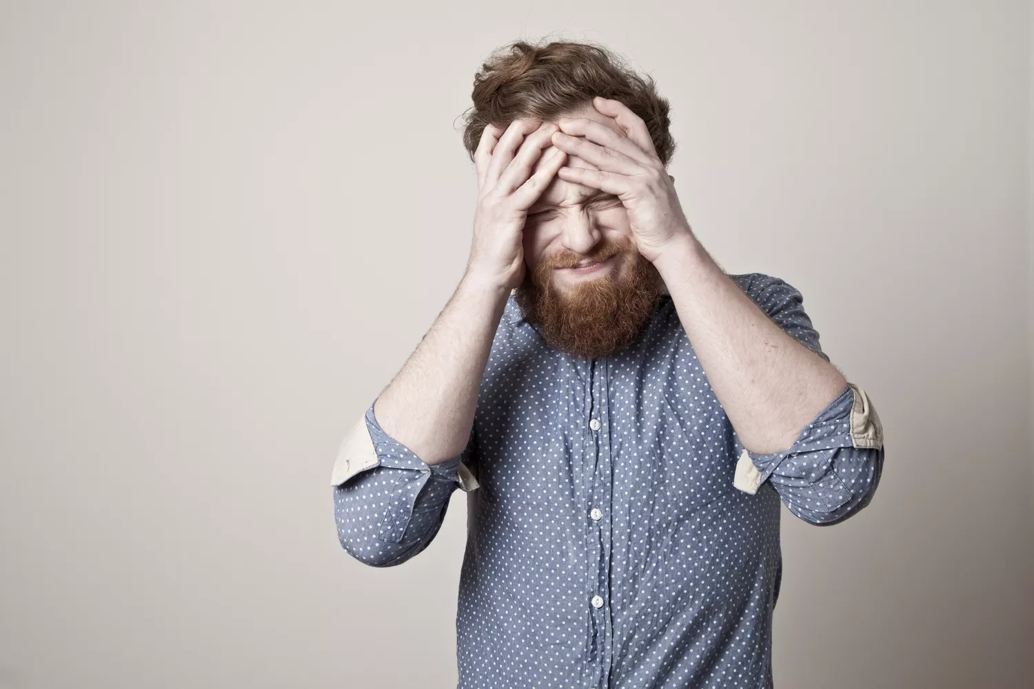 A man looking frustrated and holding his upper abdomen in pain.