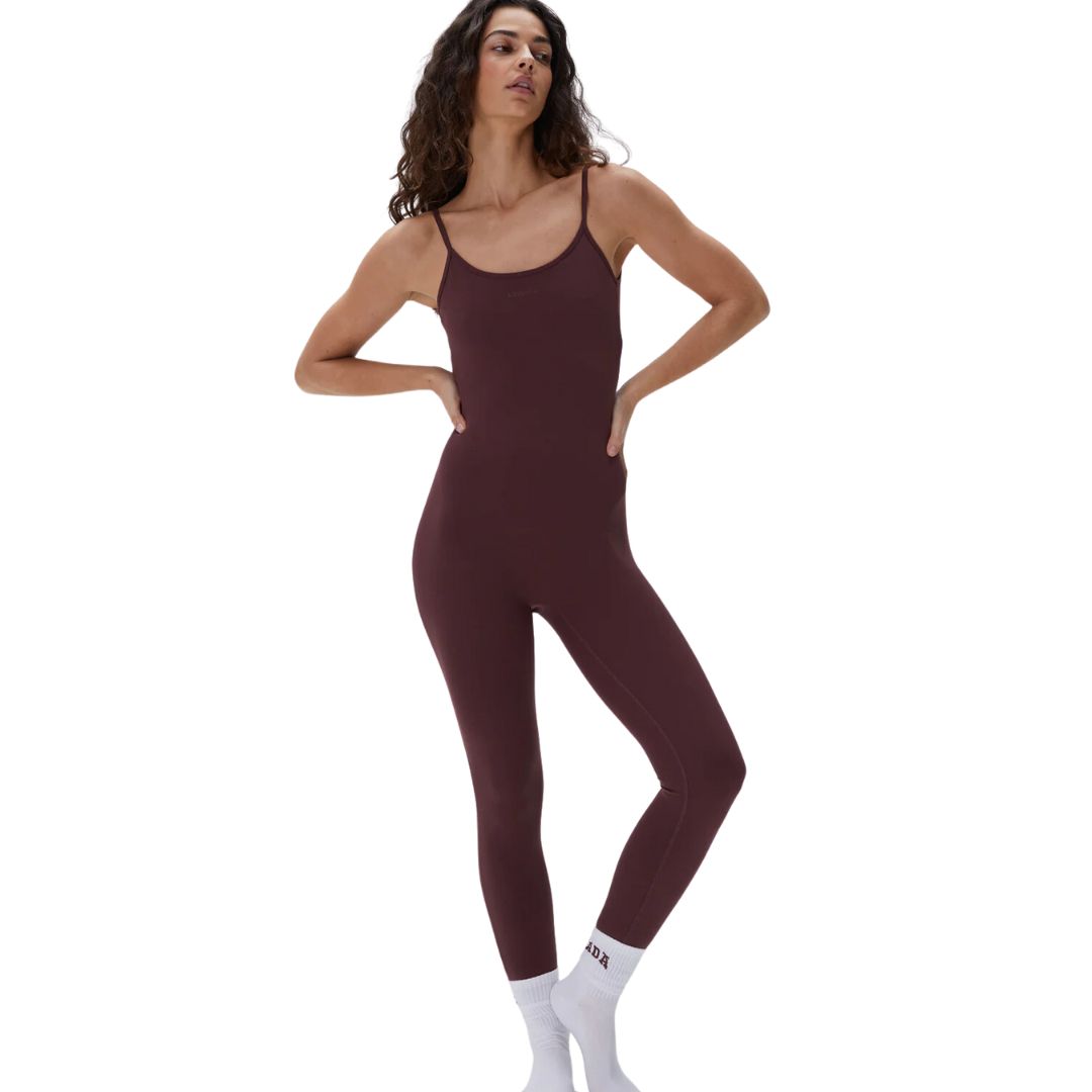 A woman wearing a burgundy unitard with a low cross-back design.