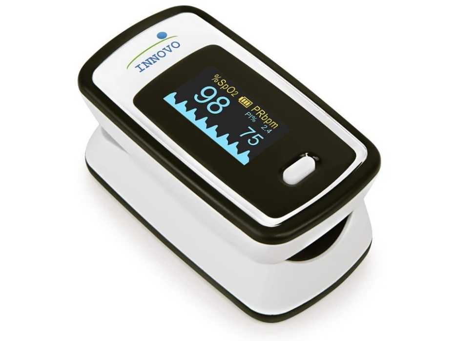 Close-up of the Innovo Deluxe pulse oximeter screen displaying a 99% SpO2 reading and 76 BPM pulse rate.