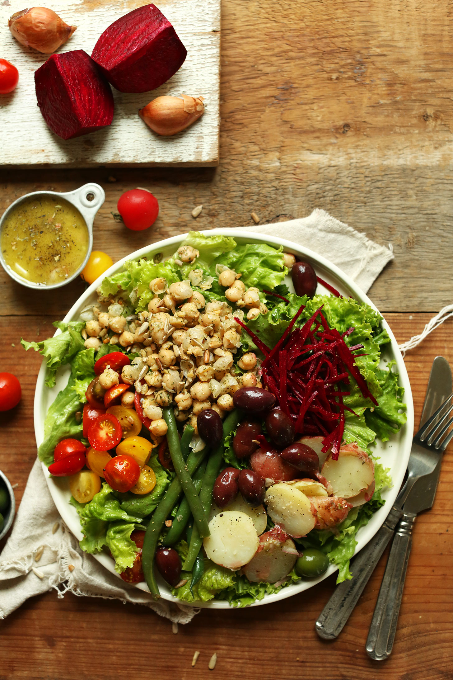 A professional plating of a plant-based Niçoise salad with ingredients arranged in distinct sections.