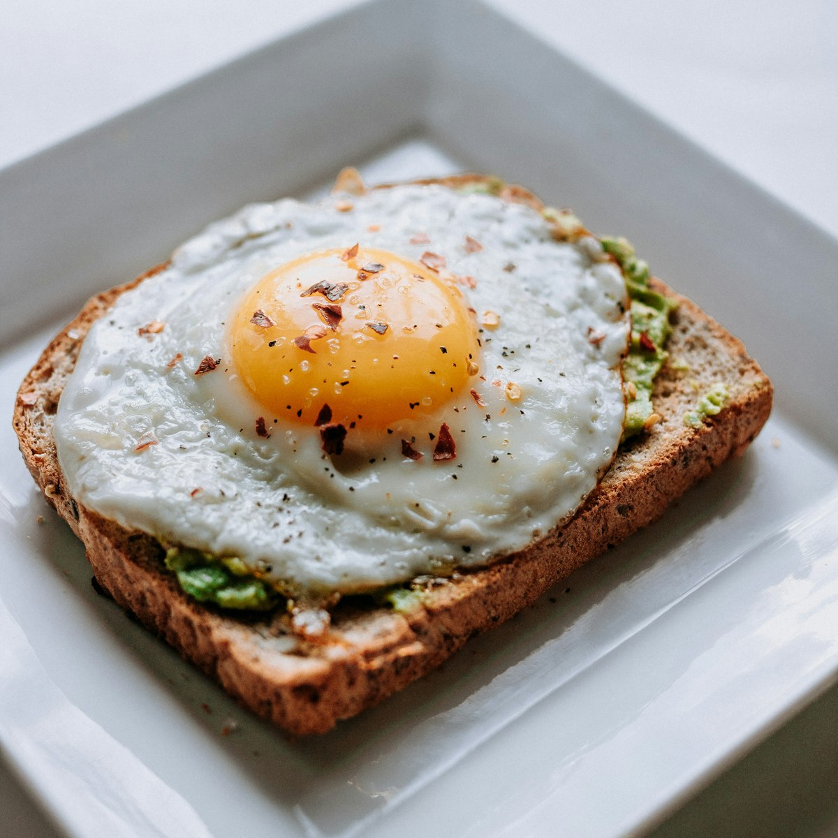 Avocado toast on sprouted grain bread topped with cherry tomatoes and fresh microgreens.