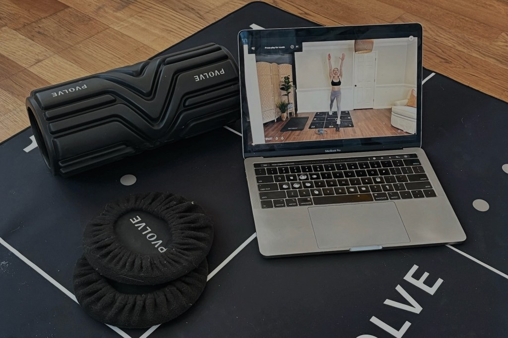 Screenshot of the Pvolve digital workout platform alongside various pieces of fitness equipment.