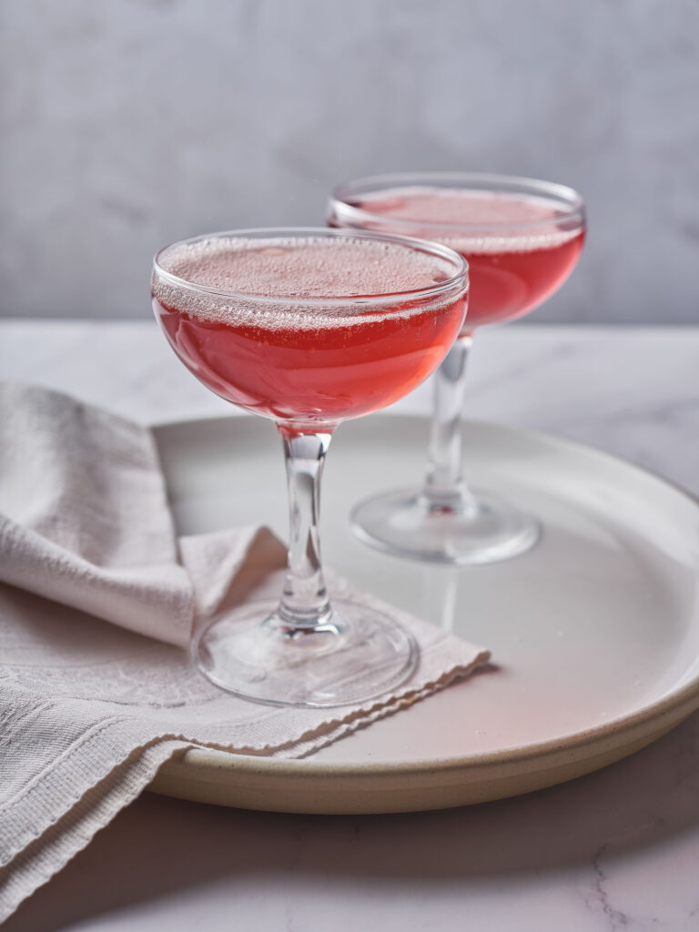 A completed Pomegranate Gin Fizz cocktail showing the emulsified foam layer.