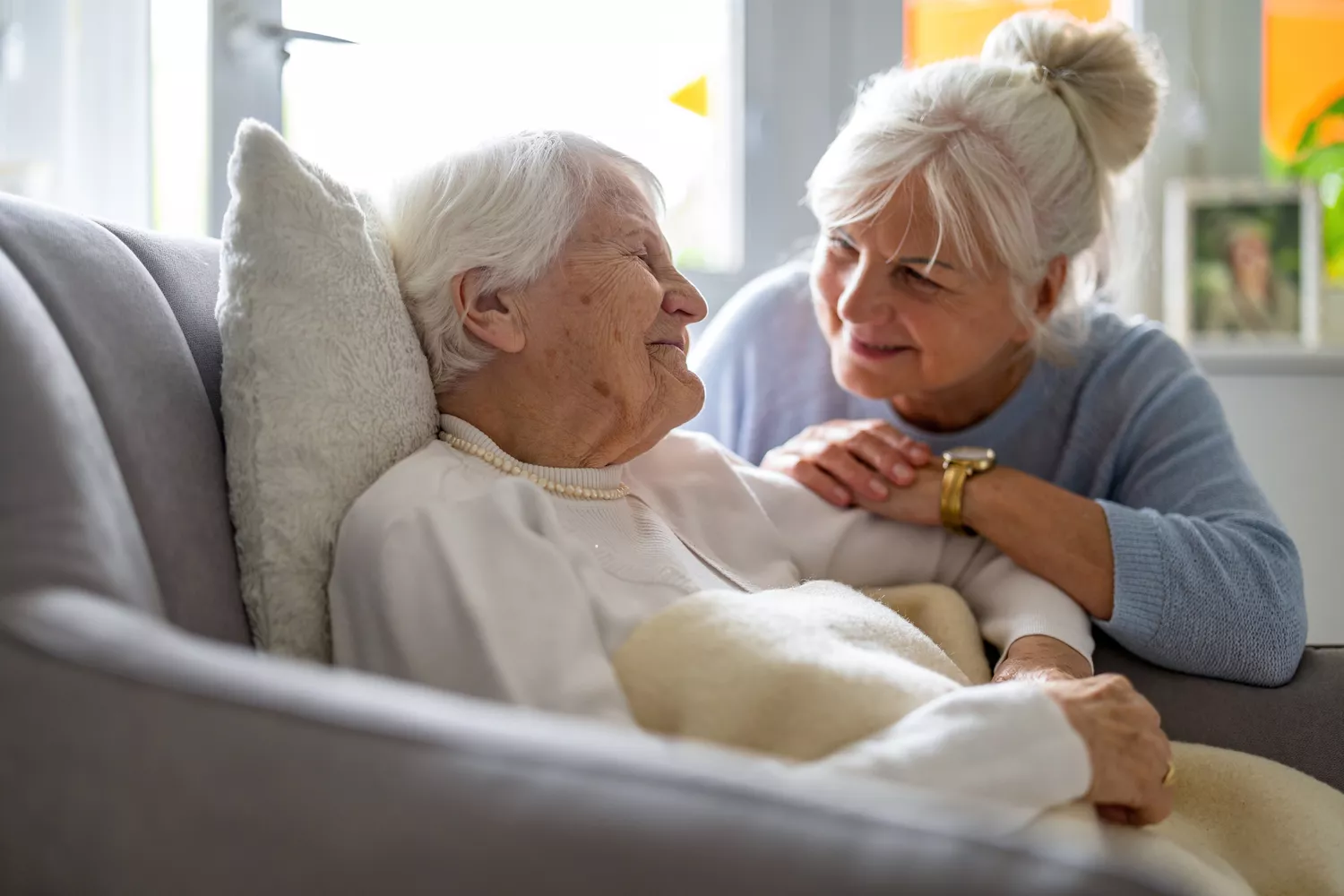 Elderly woman with caregiver at nursing home walking outdoors.