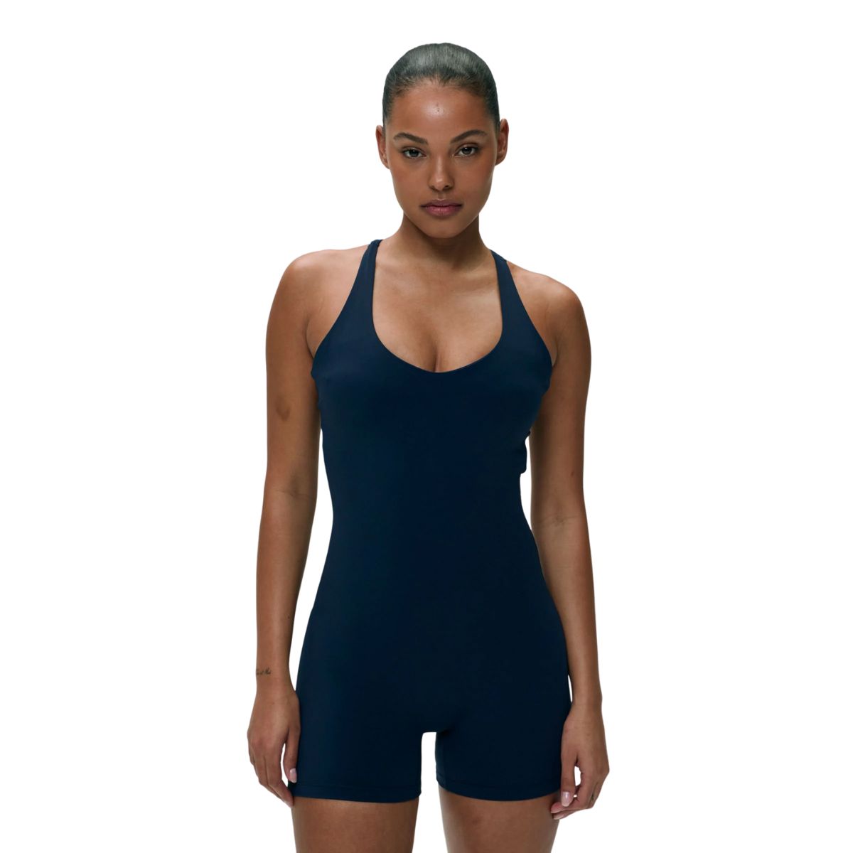 A woman posing in a navy blue racerback cut-out romper unitard.