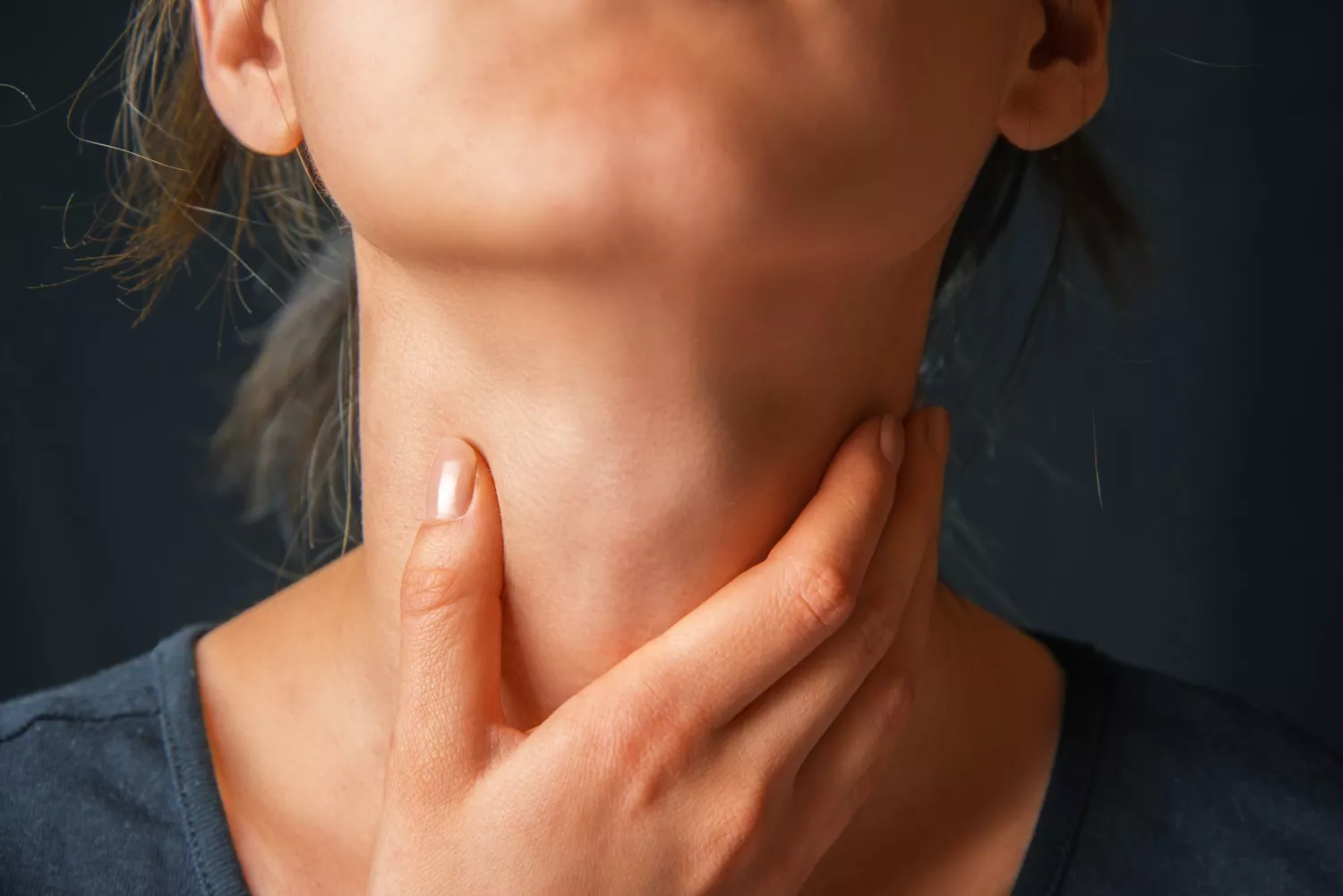 A woman checking her carotid pulse by holding her hand to her throat.