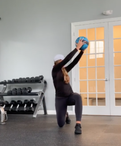 A person performing a kneeling medicine ball chop to show rotational movement in the transverse plane.