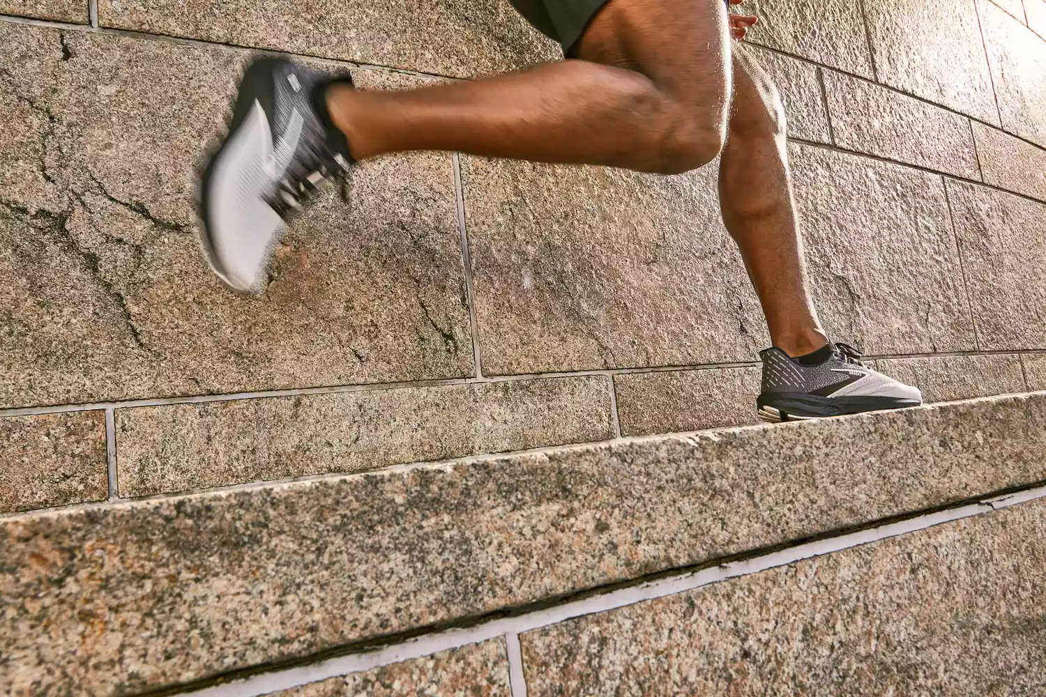 A runner wearing Brooks shoes actively running up stone steps.