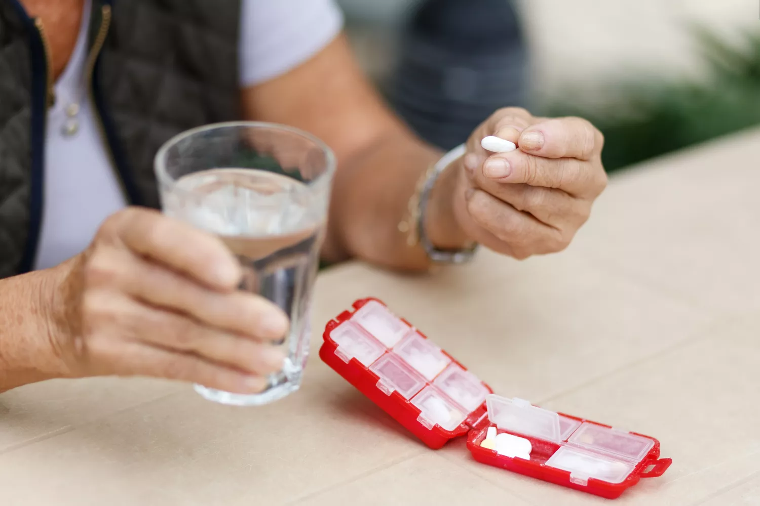 An older woman taking medication with a glass of water, representing a typical patient on GLP-1 therapy.