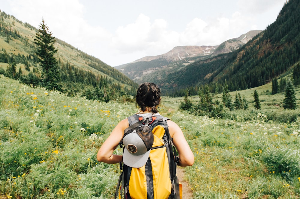 A hiker standing on a mountain peak looking out over a wide valley.