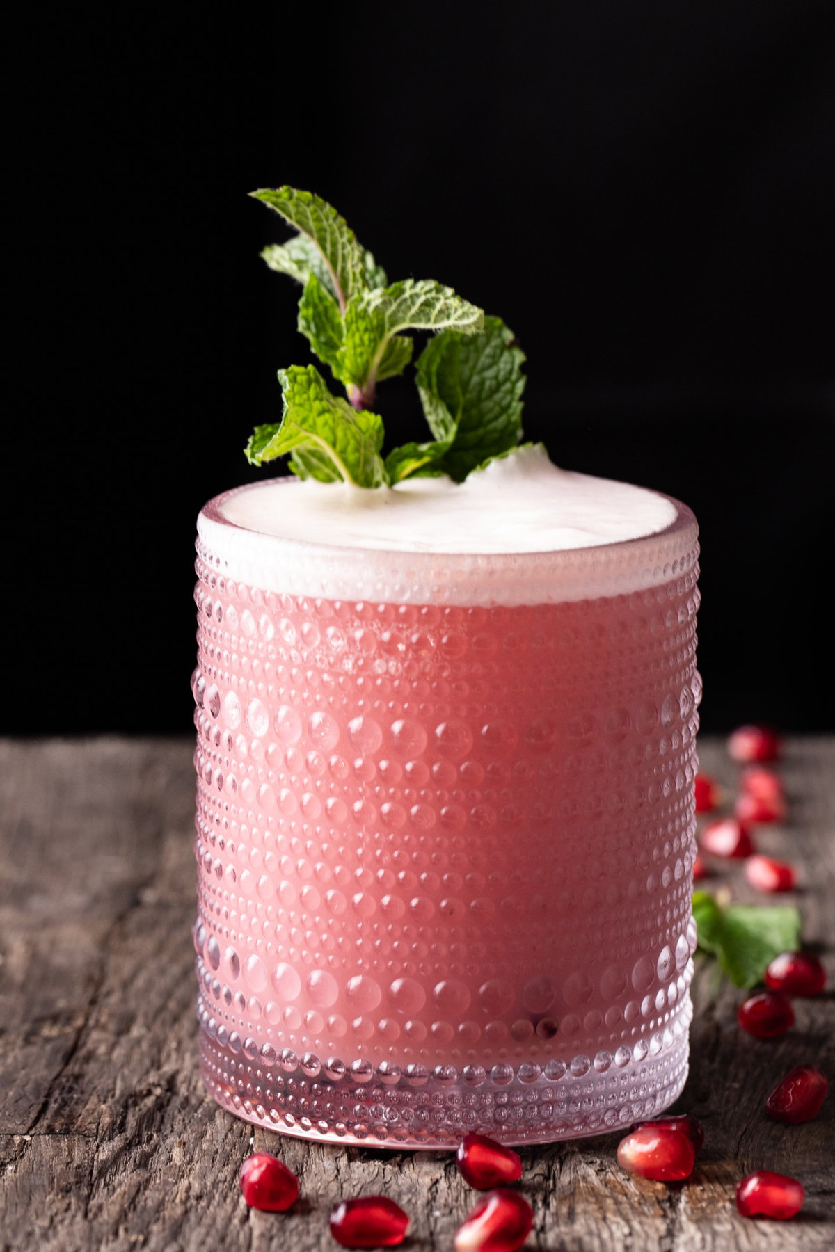 Close-up of a pink Pomegranate Gin Fizz highlighting the vibrant juice color and silky foam.