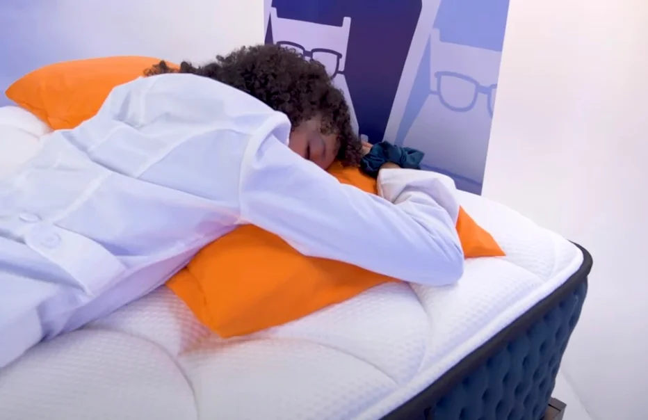 A tester demonstrating the alignment of the hips and spine while stomach sleeping.