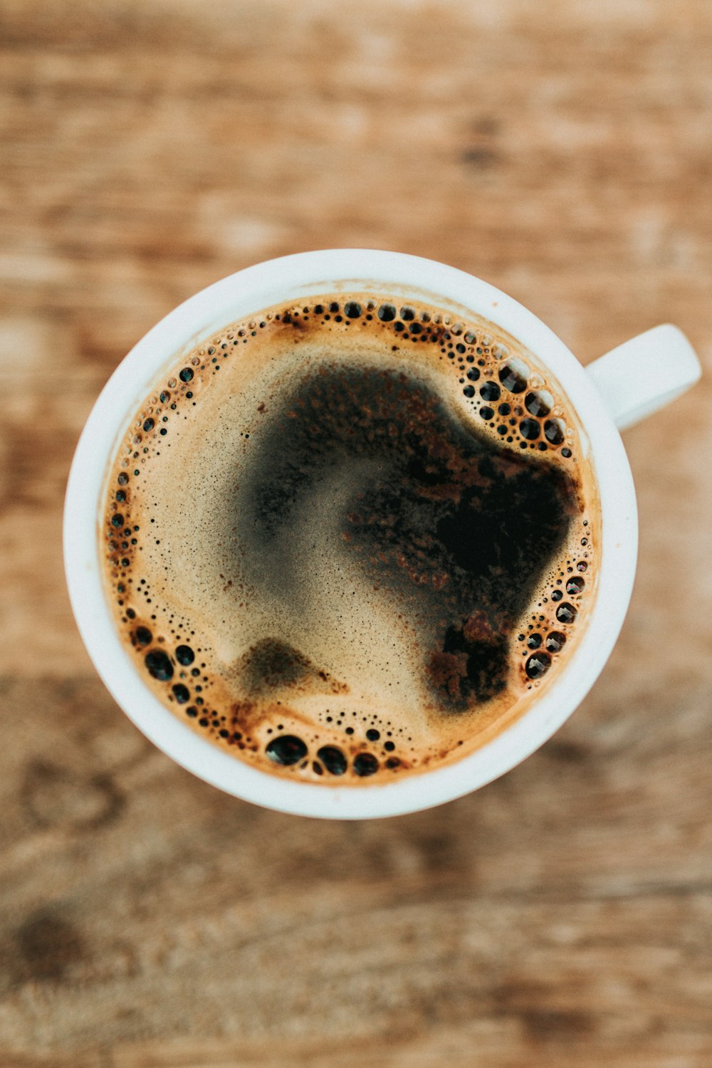 A small cup of black coffee on a clean surface.