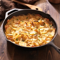 A traditional French-style dairy-free potato gratin in a ceramic baking dish, ready to be served.