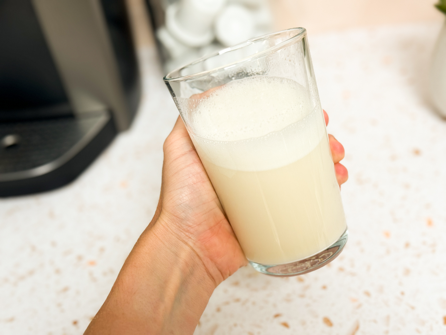 A person preparing a post-workout shake using Kaged Whey Isolate powder.