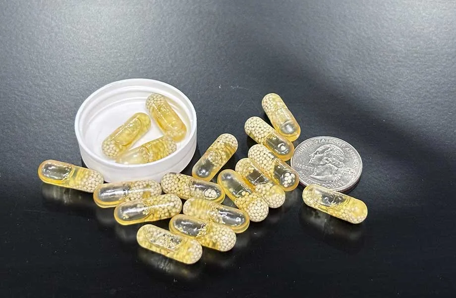 Close-up of Ritual multivitamin capsules next to a coin for size reference.