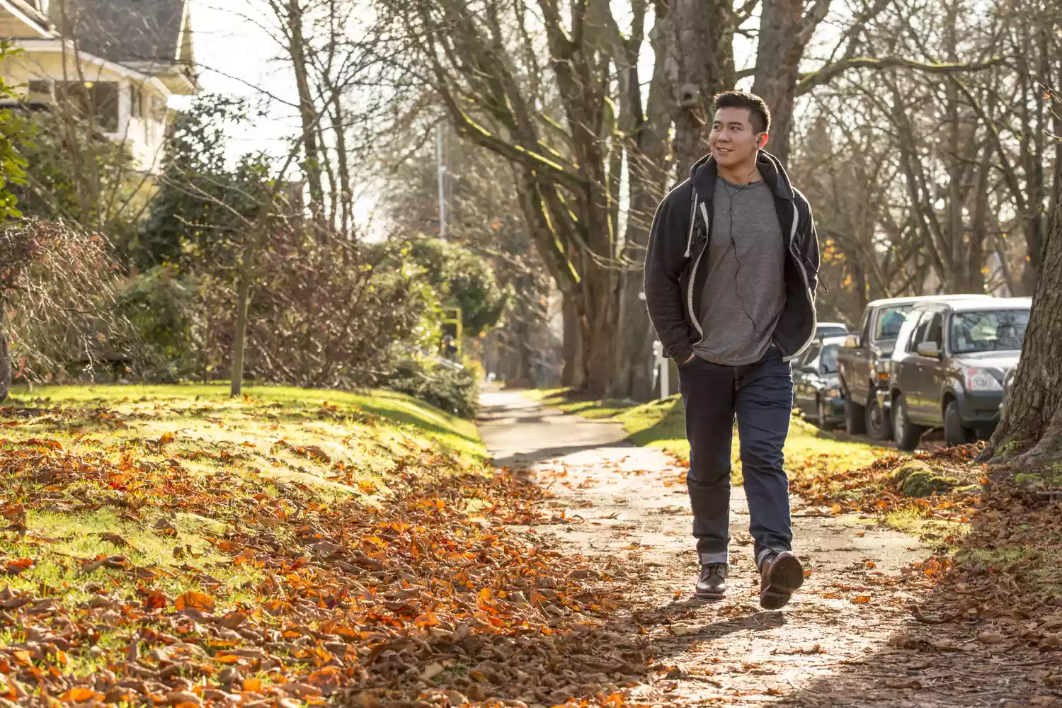 A man walking on a leaf-covered sidewalk during autumn to maintain heart health.