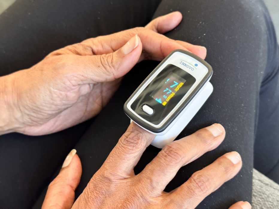 A user holding an Innovo pulse oximeter while checking their vitals.