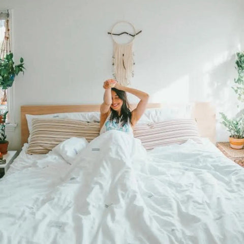 A woman waking up refreshed and smiling on high-quality organic pillows.