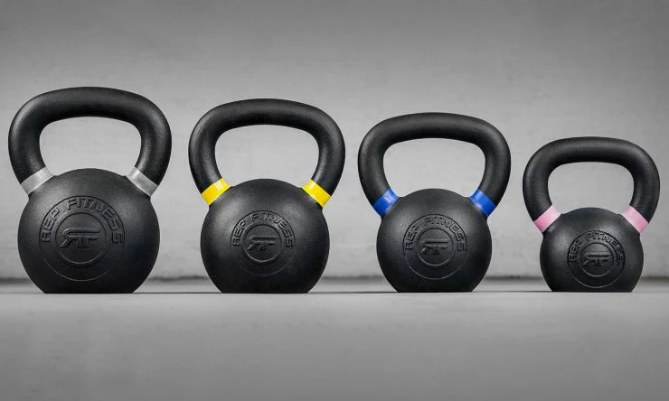 Four color-coded iron kettlebells from REP Fitness lined up by size.