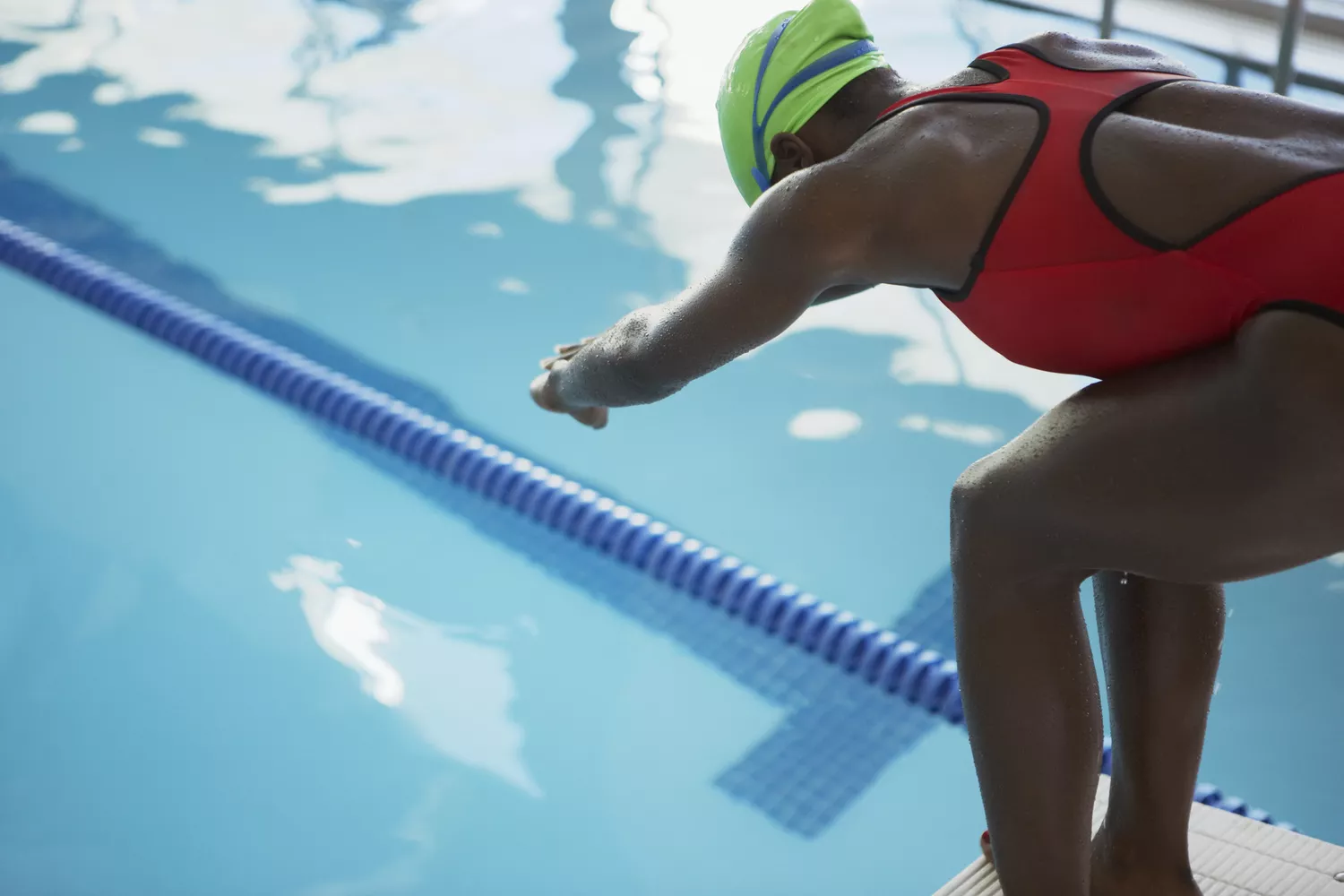 A swimmer poised at the edge of a pool, preparing to enter the water.