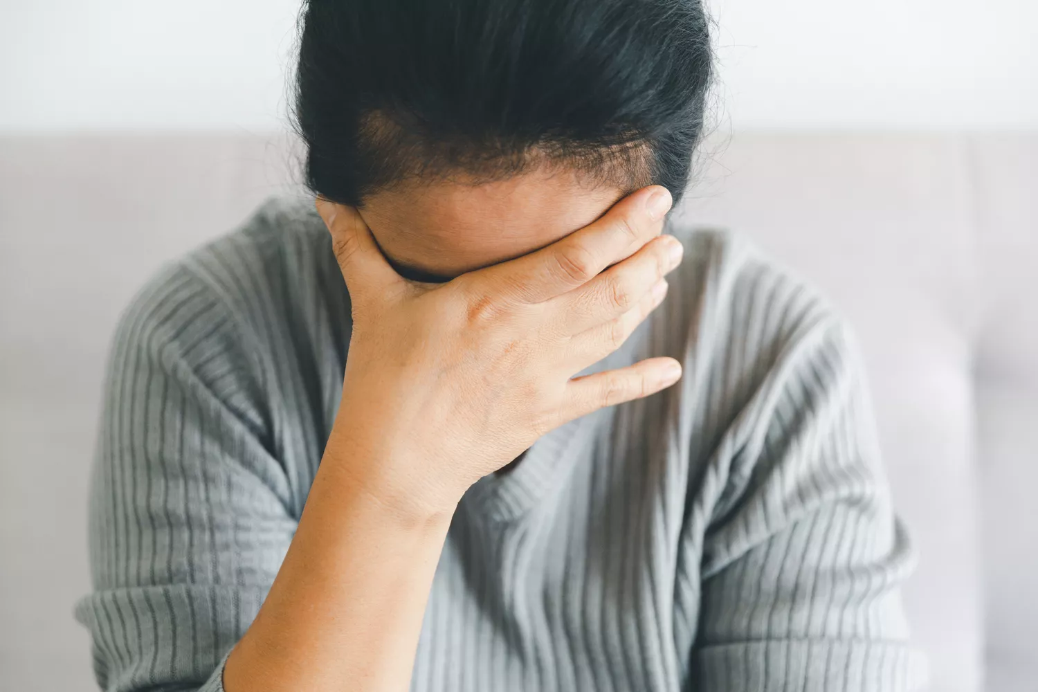 A person looking distressed with their hand on their face, representing the frustration of health insurance paperwork.