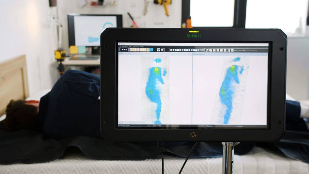 A sleep expert examining the contouring and pressure relief of a mattress.