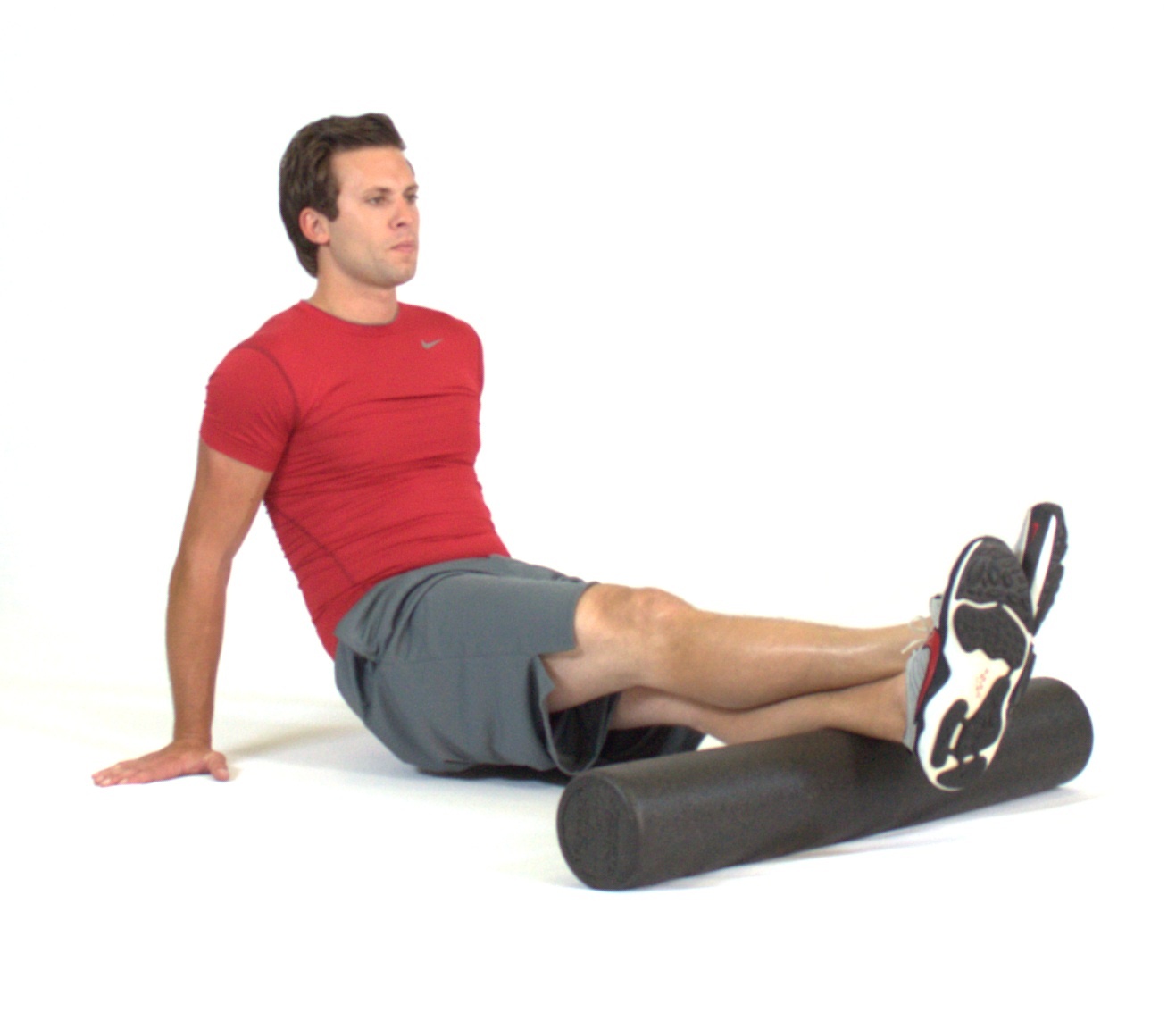 A person using a foam roller on their calf muscles while seated on a mat