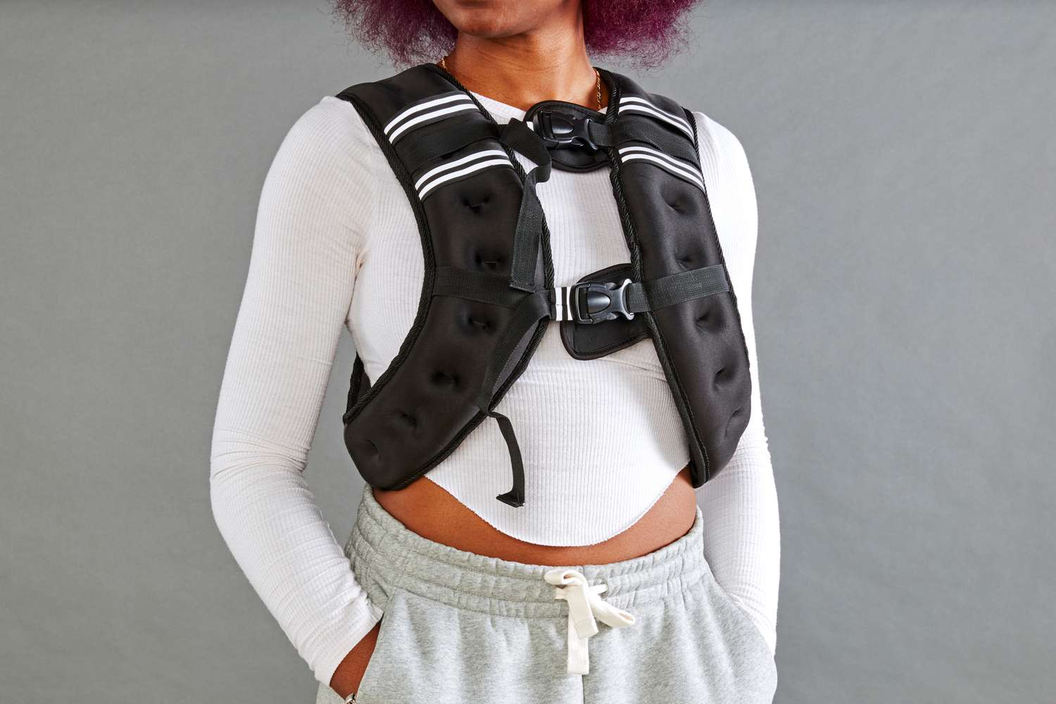 A woman wearing a black fitness weighted vest standing in a neutral posture.