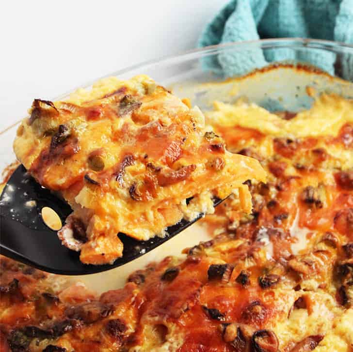 A portion of sweet potato dauphinoise being served, showing the tender layers and rich sauce.