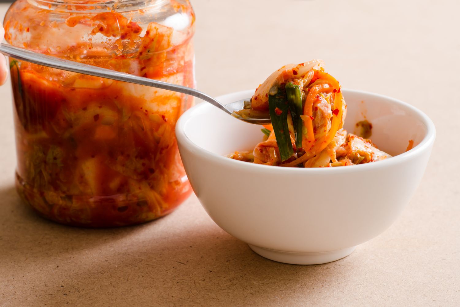 A close-up of a jar and bowl containing fermented kimchi, a natural probiotic food.