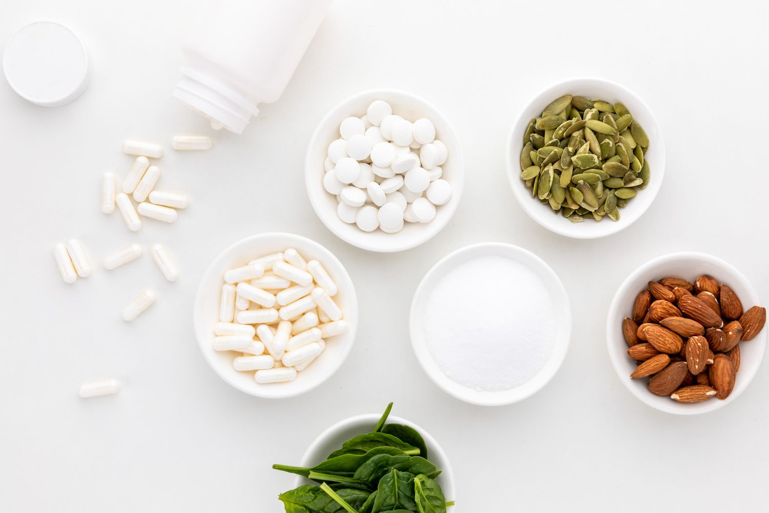 Bowl of spinach, seeds, and various magnesium capsules and powders.