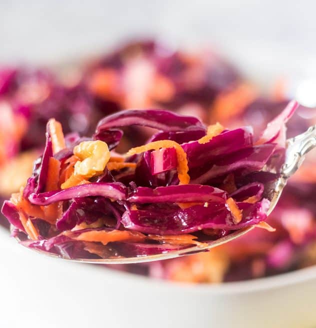 Close-up of a spoonful of red cabbage slaw with pomegranate seeds.