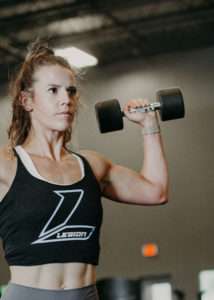 A person performing a single arm shoulder press as an example of multi-planar functional movement.