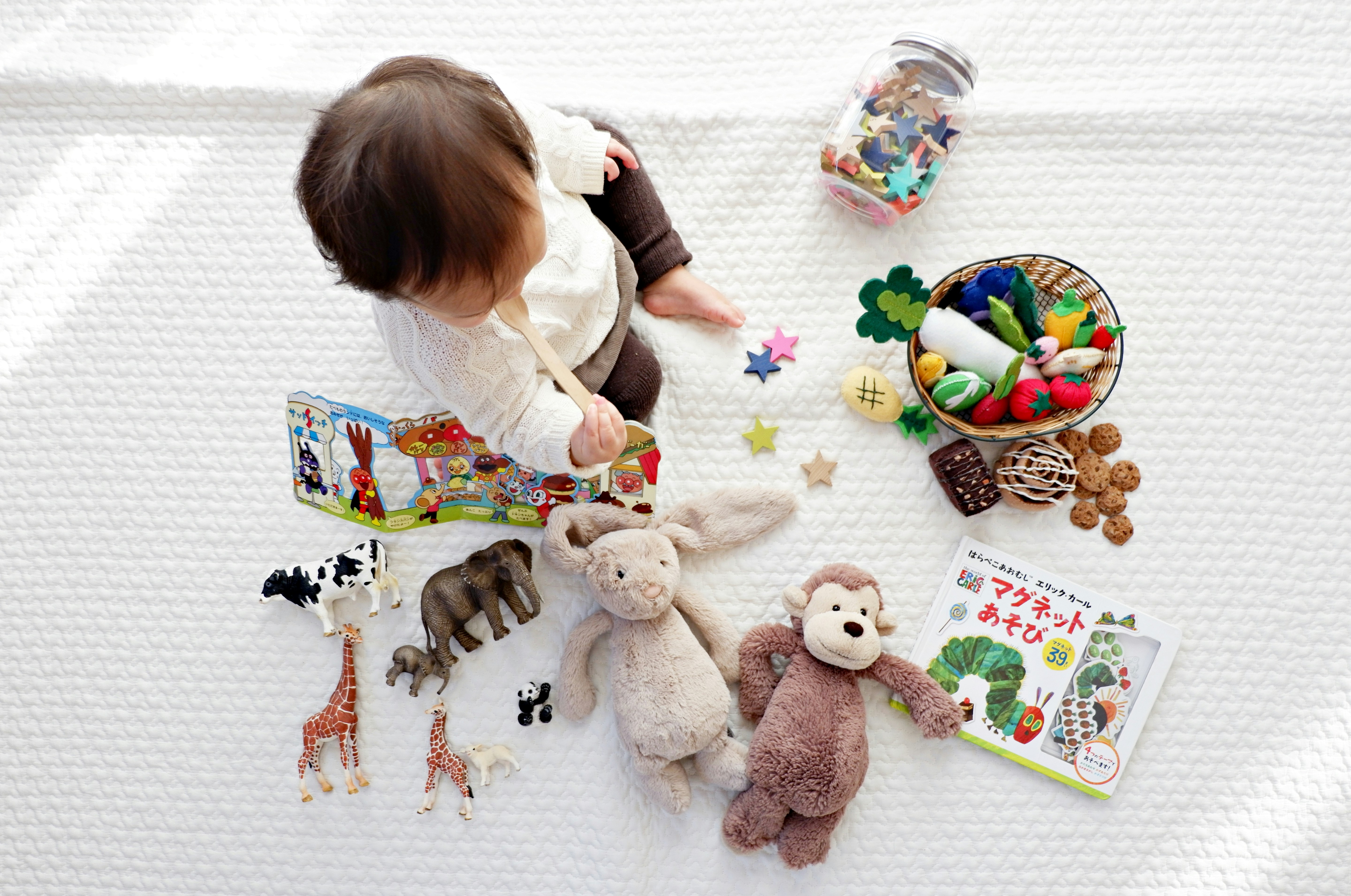 Various natural wooden toys including a camera, blocks, and a car arranged on a light surface.
