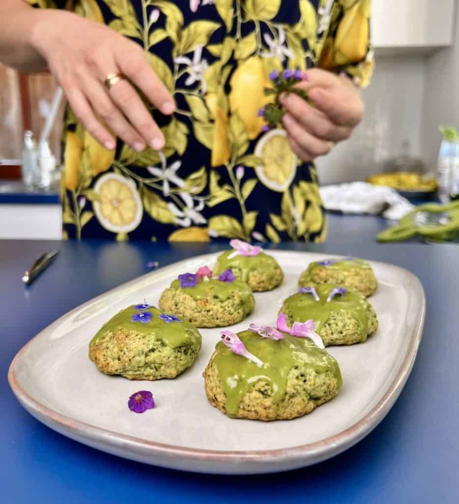 Close-up of nettle cookies decorated with green matcha icing and small edible flowers.