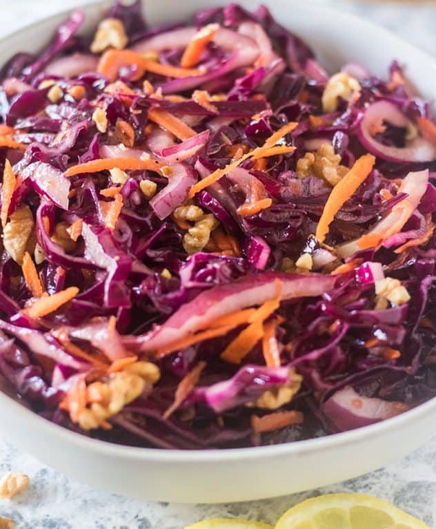 Finished red cabbage and pomegranate salad served in a white ceramic bowl.