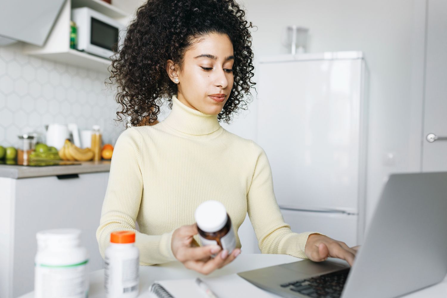A woman researching health information on a laptop in her kitchen.