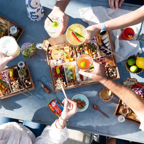 Friends sharing a charcuterie spread and cocktails at a social gathering.