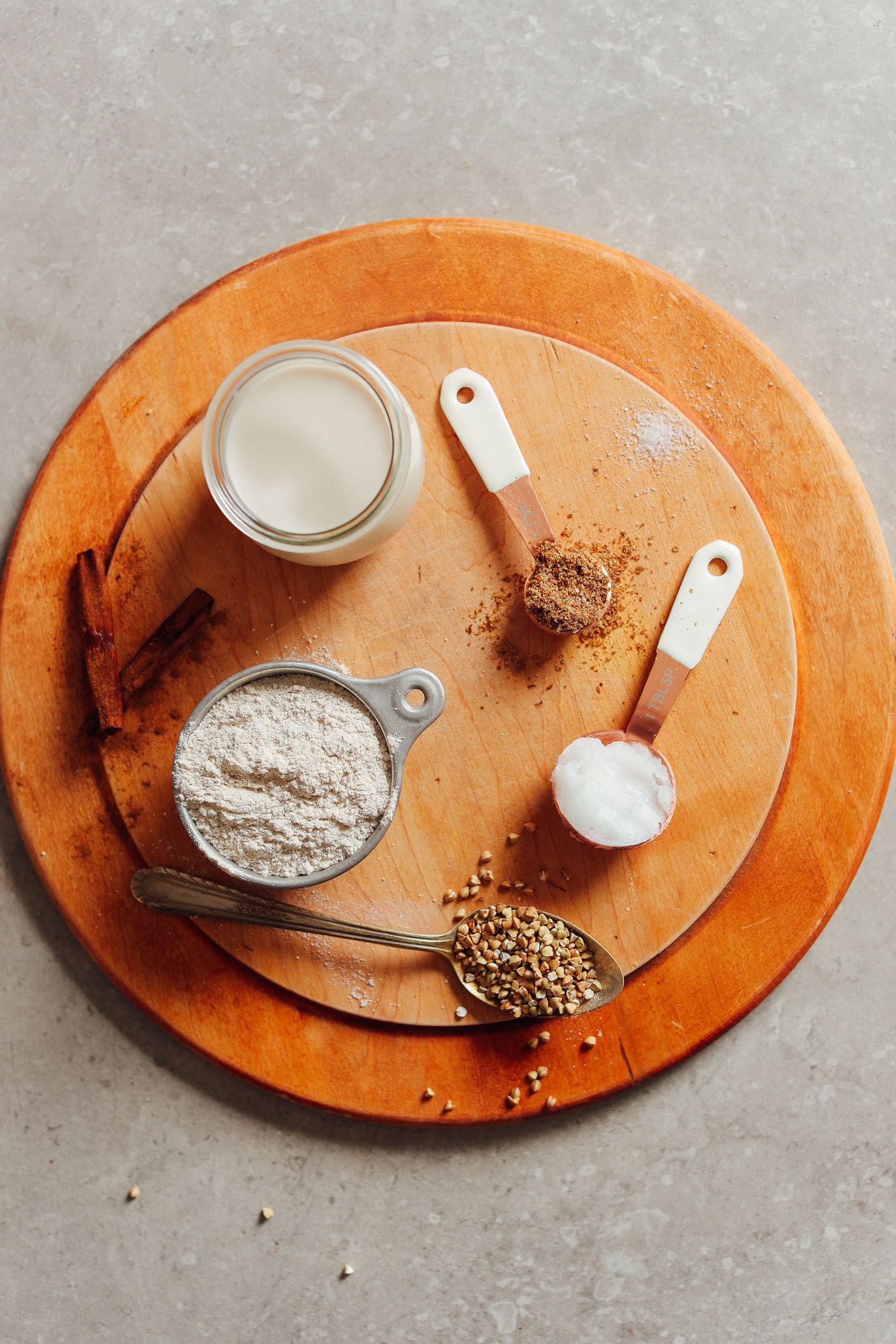 Raw ingredients for buckwheat crepes including buckwheat flour, nut milk, and coconut oil on a table.