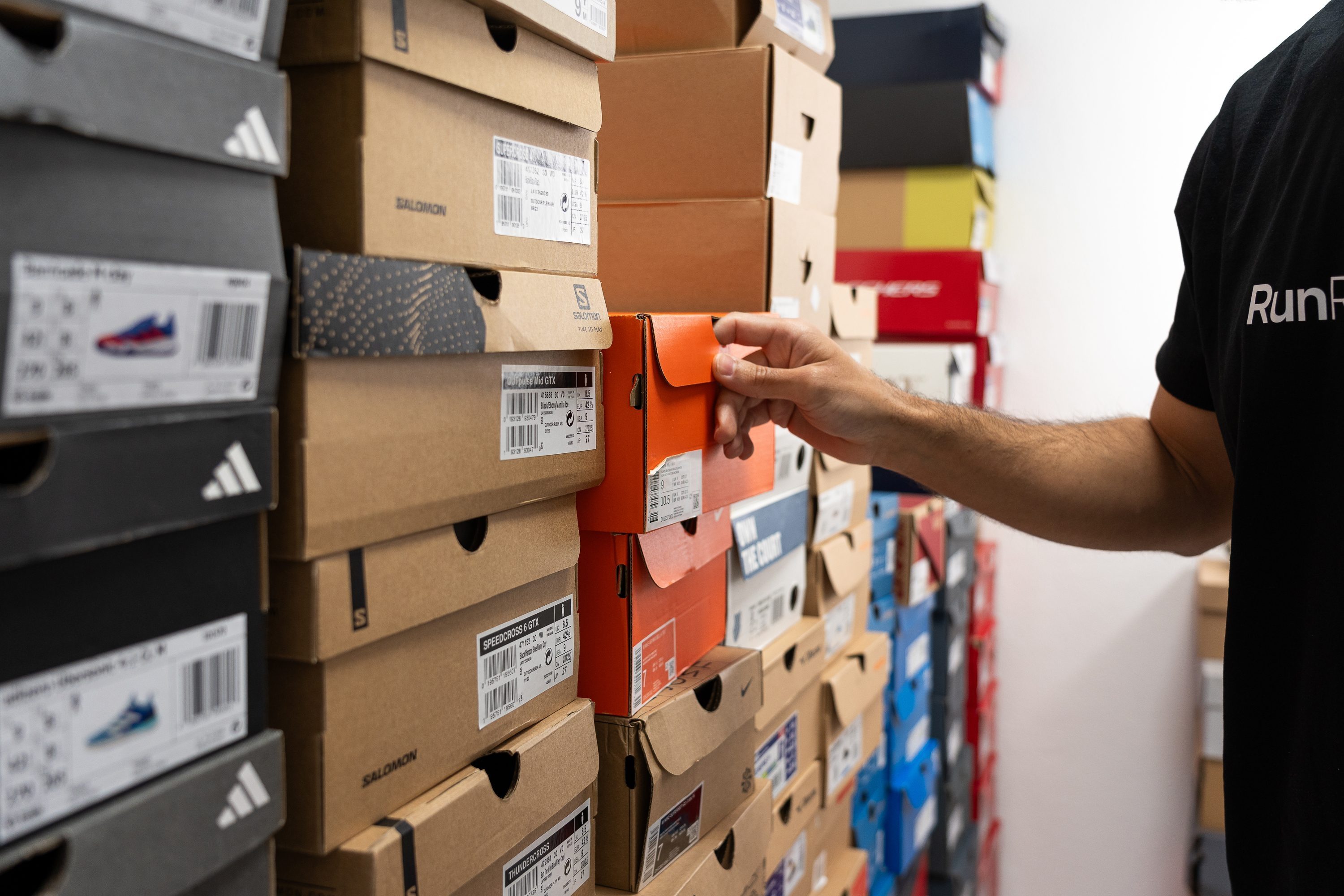 A person examining a variety of running shoes to find the right fit.