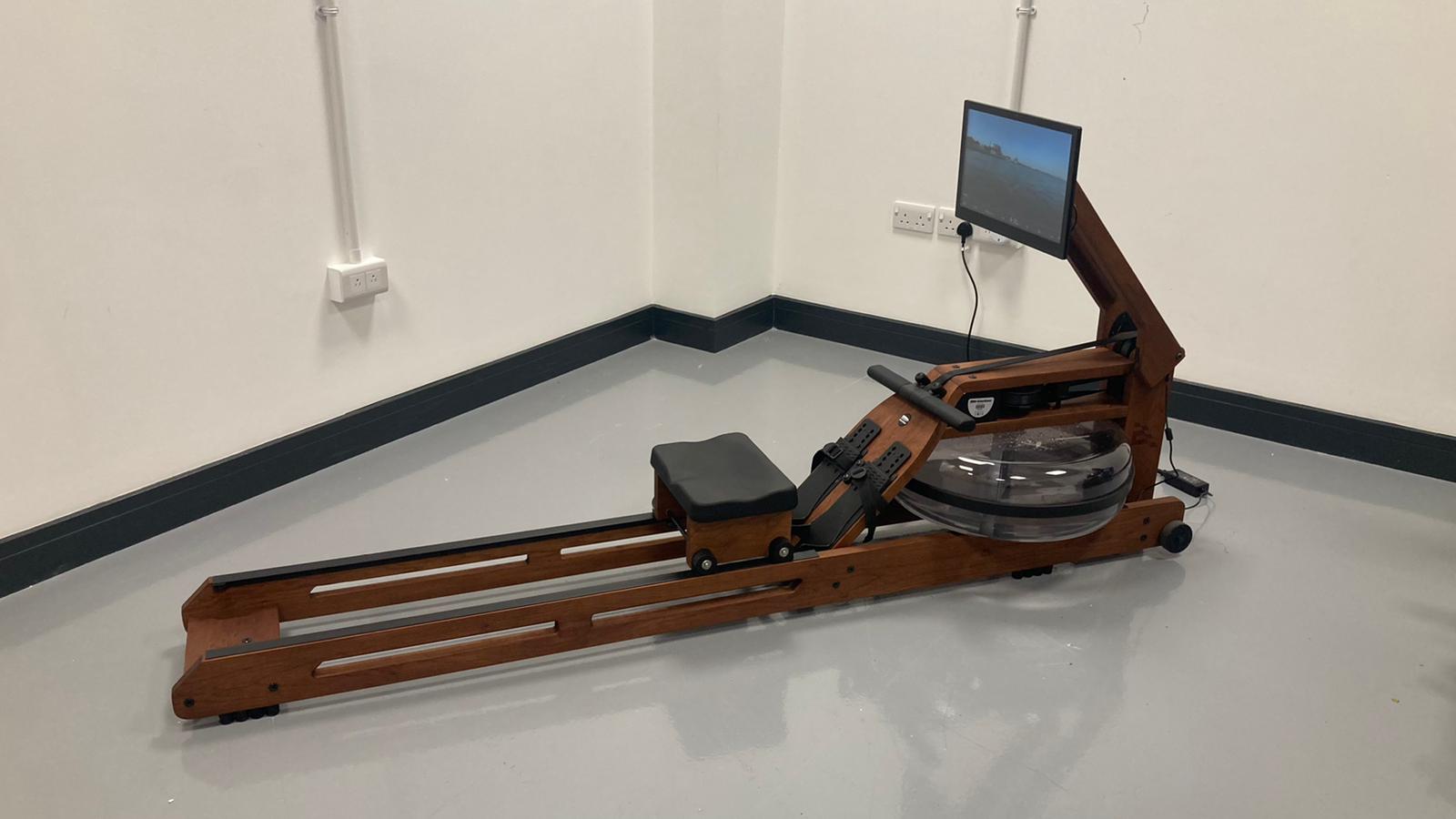 The Ergatta Rower with its handcrafted cherry wood frame positioned in a brightly lit, modern living room.