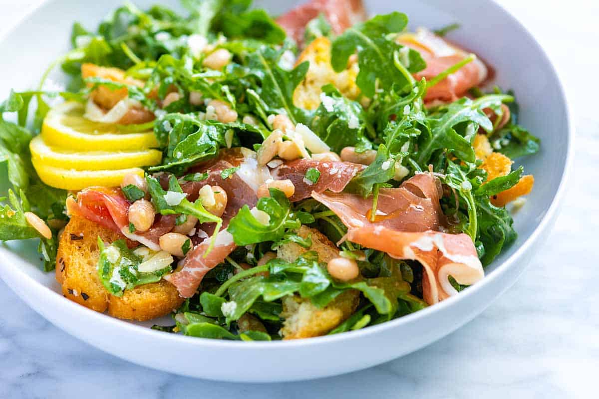 Close-up of white bean salad topped with golden garlic croutons and fresh herbs.